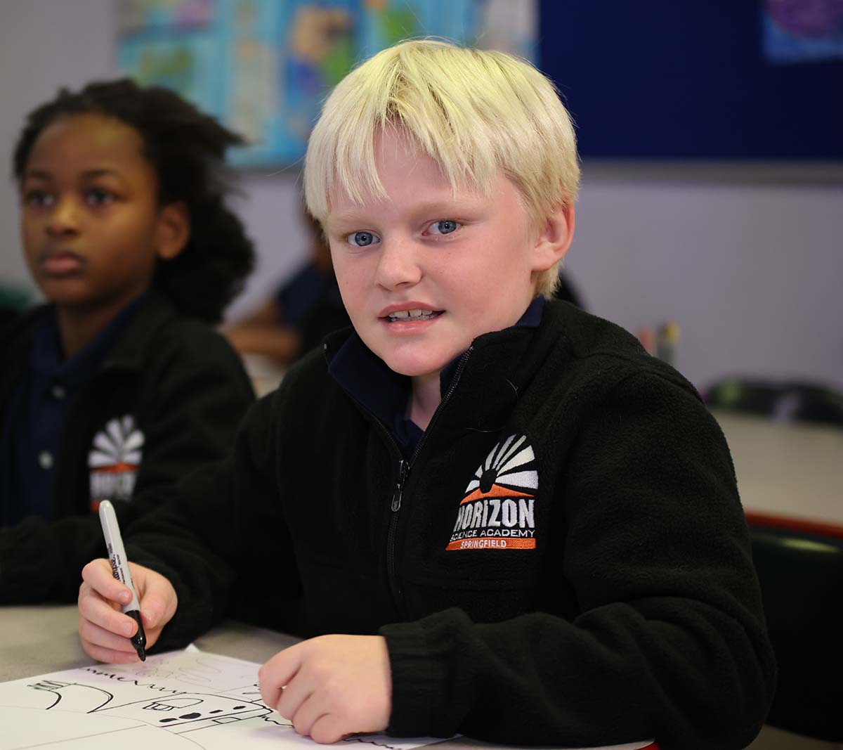 Student working on a notebook in a classroom.